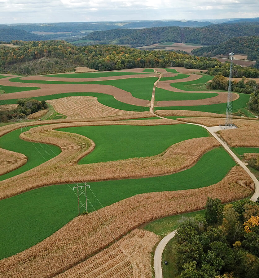 Aerial view of contour strip farming, a sustainable farming practice that preserves soil by alternating crops and grass.