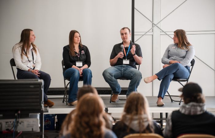 four speaker sitting in chairs on a stage